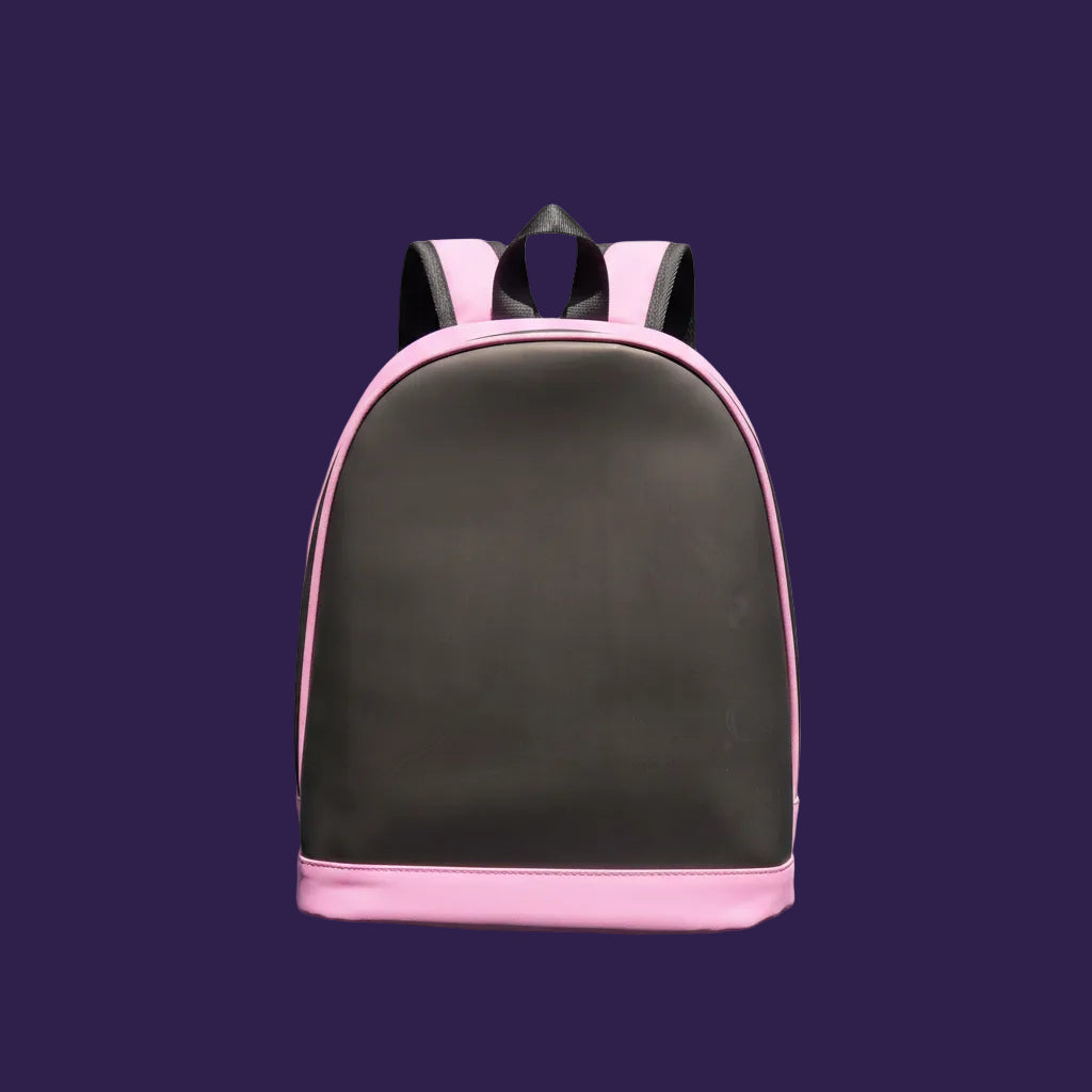 A pink and gray backpack or school bag lying flat on a ribbed green surface, photographed in bright sunlight with a strong shadow.