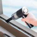 Hand using a handheld vacuum cleaner to clean a window