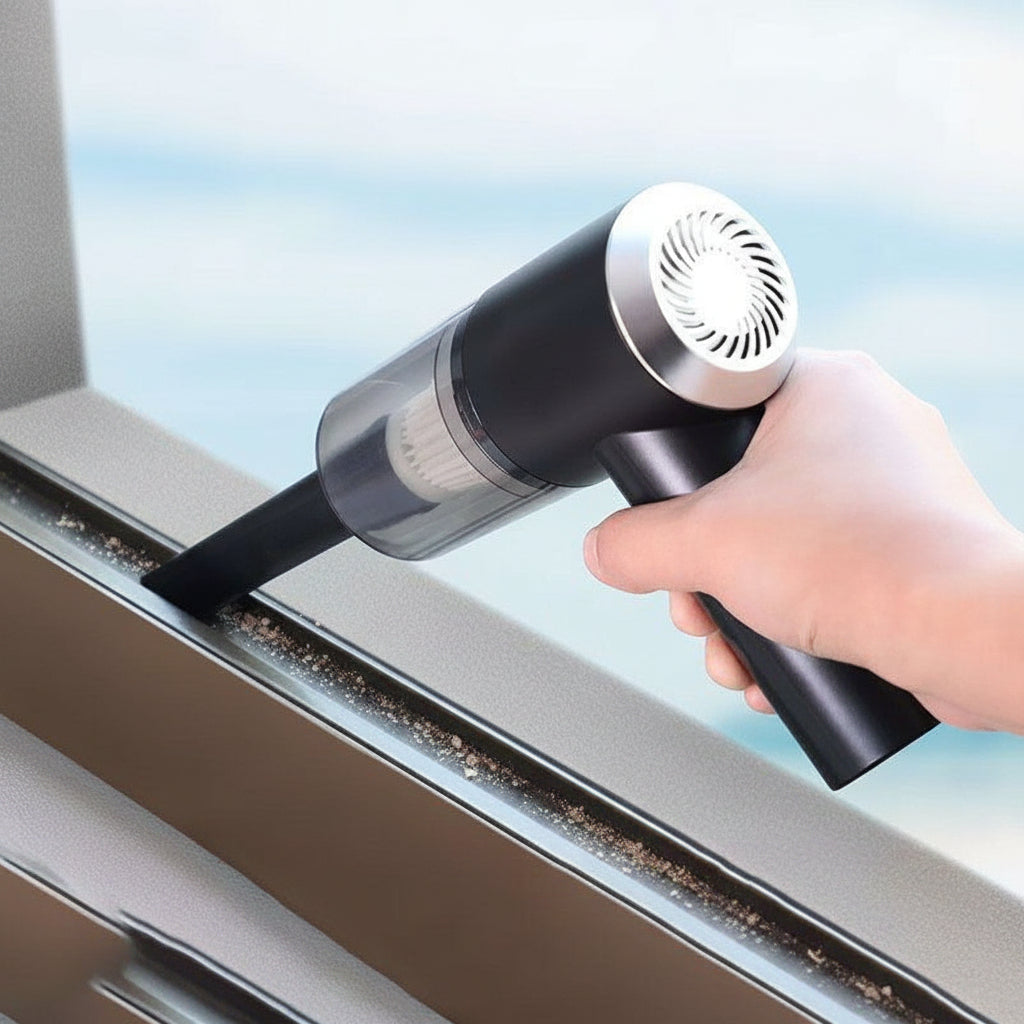Hand using a handheld vacuum cleaner to clean a window