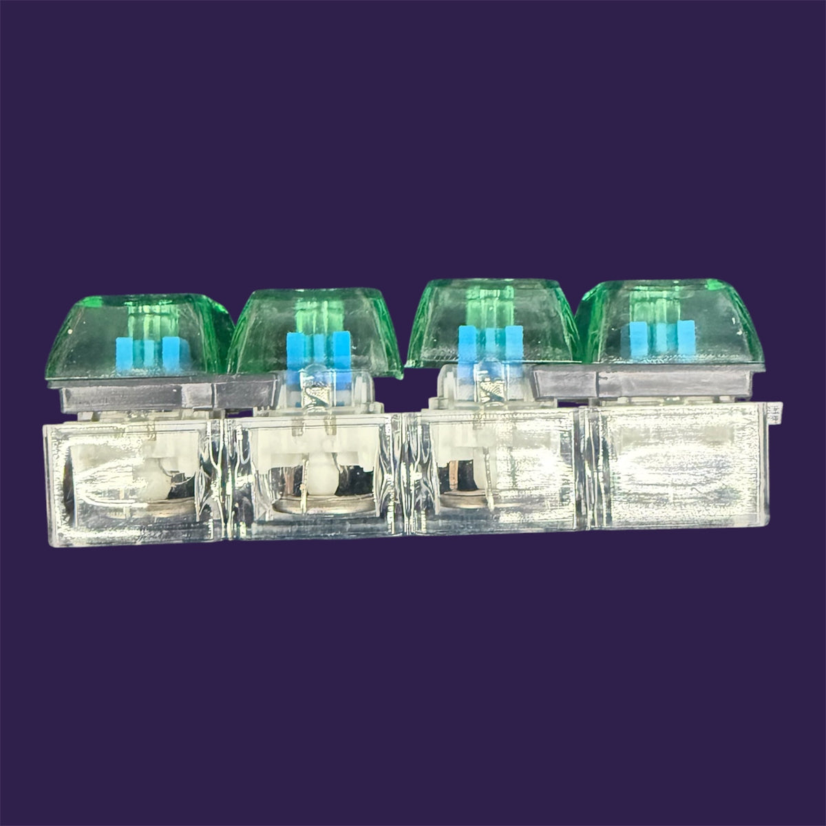 Translucent mechanical keyboard switches with cyan stems and moss-green keycaps on purple background