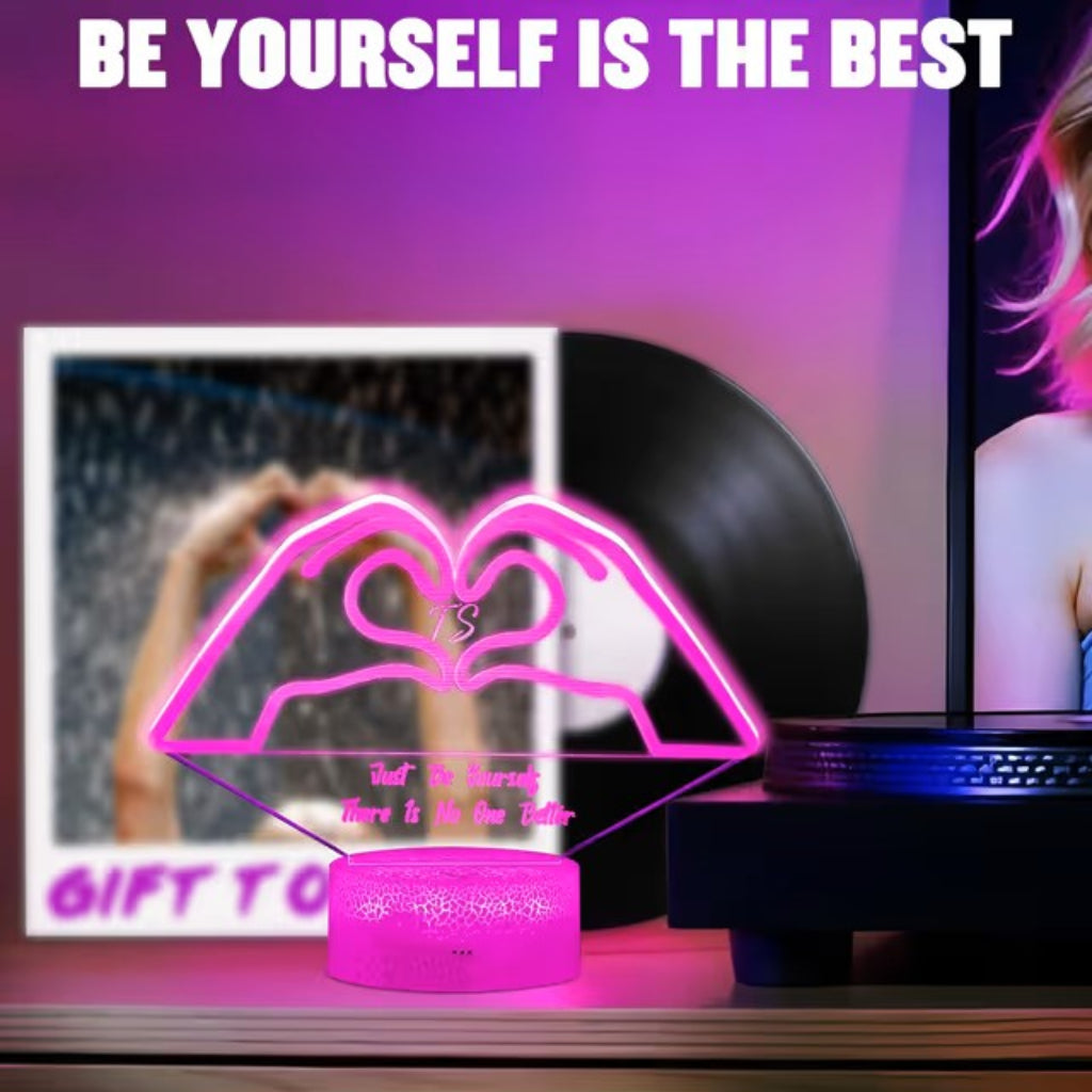A pink LED acrylic lamp shaped like lips forming a heart, glowing on a wooden shelf next to a vinyl record and a framed photo. The scene has a purple-pink ambient glow, and the text 'BE YOURSELF IS THE BEST' appears at the top.