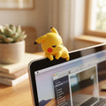 Cute Pokémon Hipper figure attached to a laptop monitor in a cozy home office setup